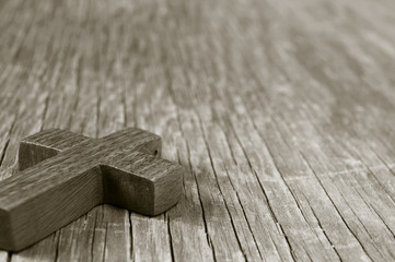 wooden Christian cross on a rustic wooden surface, sepia toning