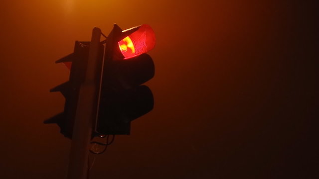 Traffic light in fog. Night and misty weather.