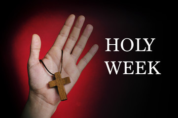 man hand with a wooden cross and the text holy week