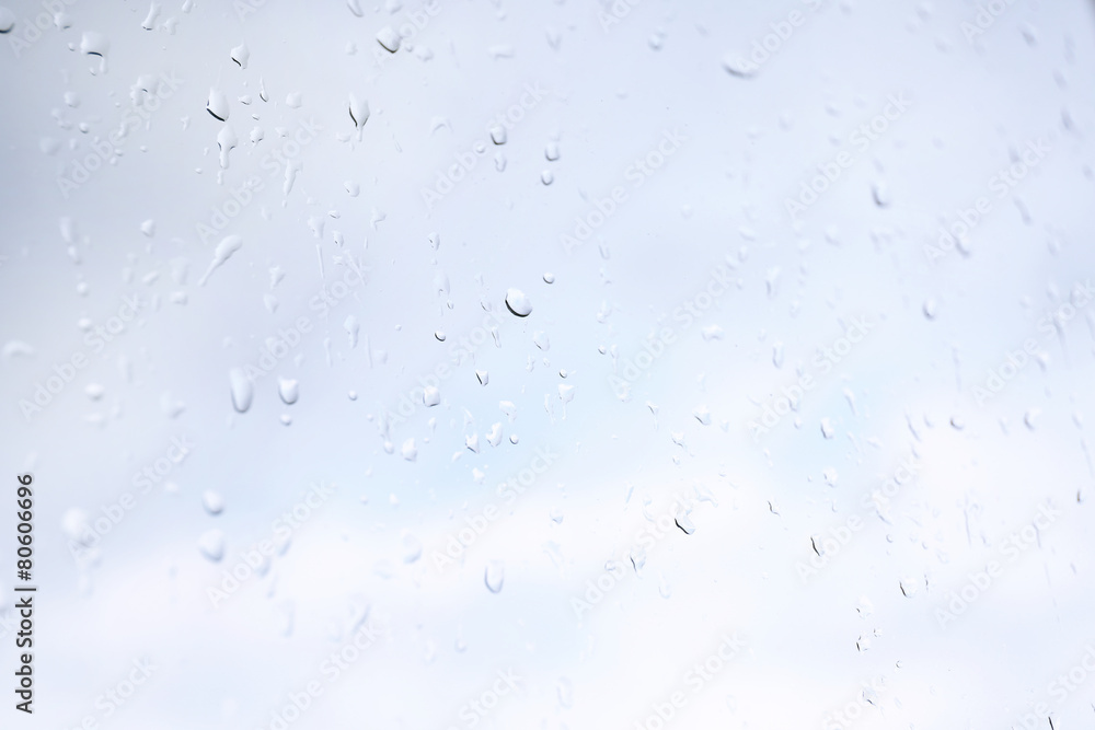 Sticker Raindrops on glass window overlooking the street on background