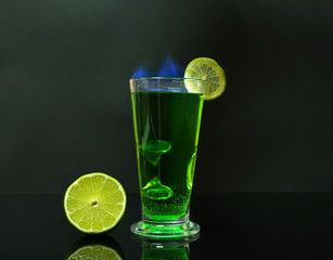 Flaming green cocktail on dark background