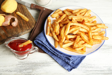 Tasty french fries on plate, on wooden table background
