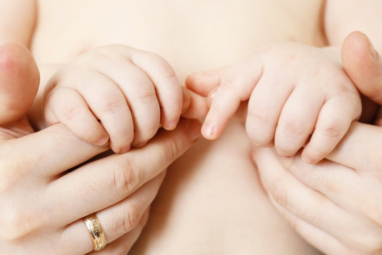 Baby hand holding mother finger, close-up