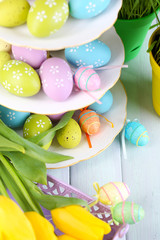 Fototapeta na wymiar Easter eggs on vase and tulips on table close-up