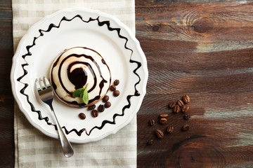 Tasty panna cotta dessert on plate, on wooden table