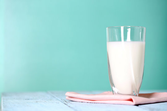 Glass of milk on wooden table on blue background