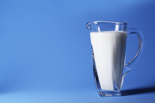 Pitcher of milk on blue background