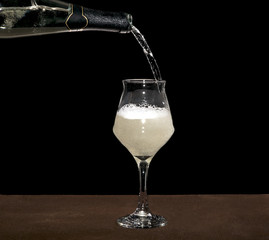 White wine bottle pouring wineglass