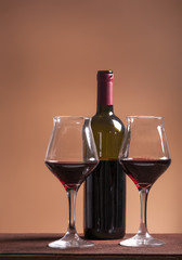Red wine bottle with two filled wineglasses