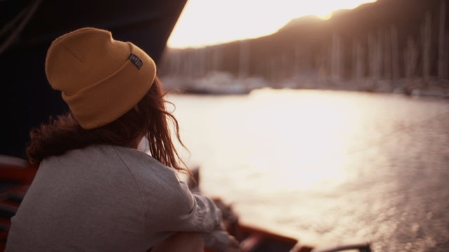 Teen grunge girl sitting alone on dock at the harbor