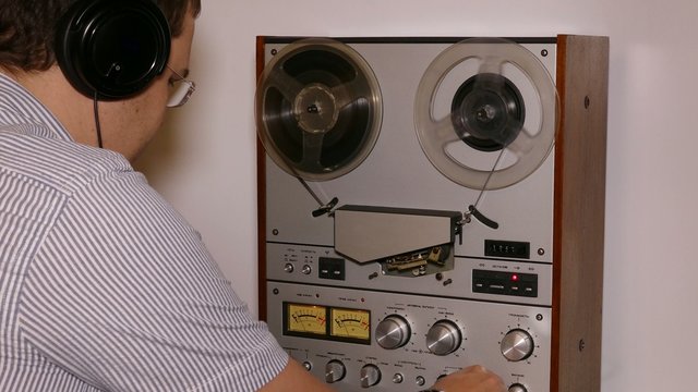 man with headphones working with reel tape recorder - 4k