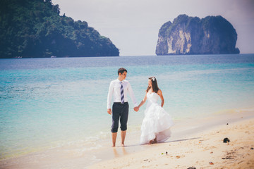 Fototapeta na wymiar groom and bride walk on sand beach