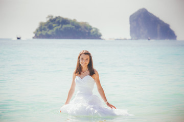 Fototapeta na wymiar bride in white dress smile standing in azure water