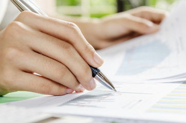 Woman evaluating charts and documents on paper