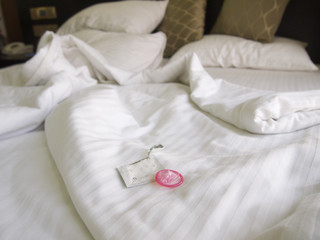Obraz na płótnie Canvas Messy bed in a hotel with a pink condom