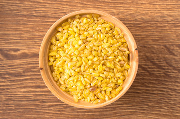 Cereal bulgur in a wooden bowl closeup
