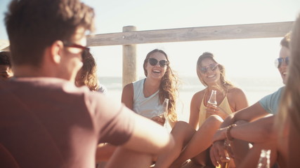 Group of friends relaxing and drinking beer at the beach - Powered by Adobe