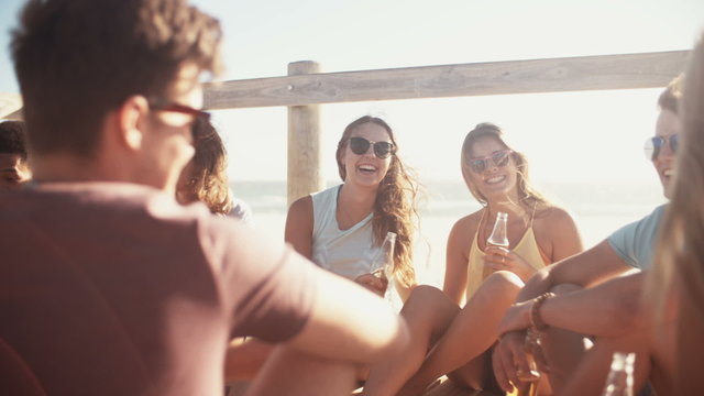 Group of friends relaxing and drinking beer at the beach