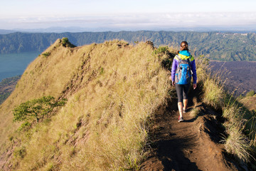 Girl tourist with a backpack walking on top of the mountain and
