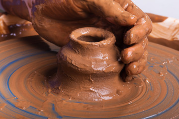 hand of potter with clay jug on pottery wheel