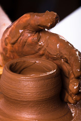 hand of potter working on pottery wheel, closeup