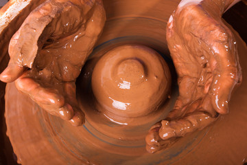 hands making clay pot on pottery wheel