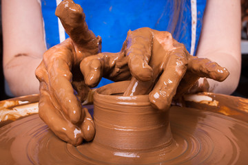 Hands of a potter, creating a clay jug on pottery wheel