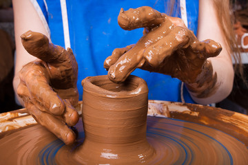 hands of a woman which learning to work on the pottery wheel