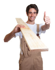 Schreiner mit Holzbrett zeigt den Daumen