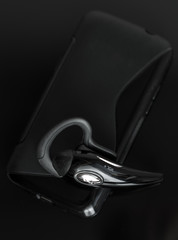 Close-up of handsfree bluetooth device near mobile phone.