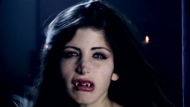 Sensual woman vampire with blood in mouth scary extreme closeup