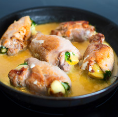 Chicken roll with herbs and cheese in frying pan.