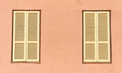 Two window with yellow shutters. Close-up view.
