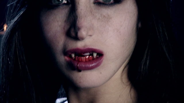Sensual woman vampire with blood in mouth scary extreme closeup