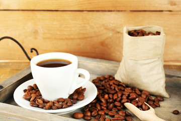 Cup of coffee with beans on tray and rustic wooden background
