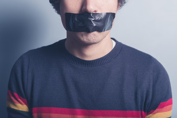 Young man with tape covering his mouth