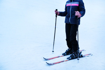 Human legs with skis over white snow background