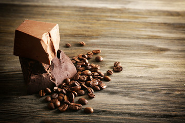 Chocolate bars with coffee beans on wooden background