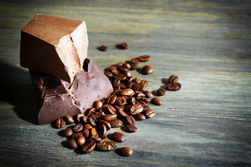 Chocolate bars with coffee beans on wooden background