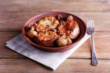 Baked potatoes with mushrooms in bowl on wooden table