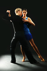 Beautiful couple of professional artists dancing on black background
