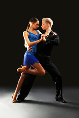 Beautiful couple of professional artists dancing on black background