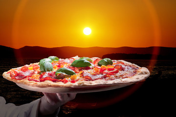 Pizza mit Hand und Sonnenuntergang Nahaufnahme