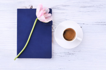 Fresh tulip, diary and cup of coffee on wooden table, top view