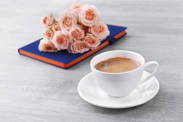 Fresh roses with diary and cup of coffee on wooden background