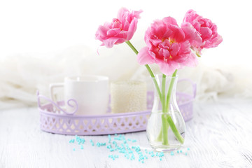 Fototapeta na wymiar Pink tulips in glass vase on wooden table, closeup