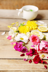 Fototapeta na wymiar Cup of herbal tea with beautiful flowers, on wooden background