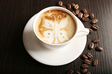 Cup of latte art coffee with grains on wooden background