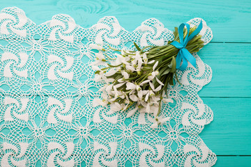Snowdrops on lace tablecloth on wooden background