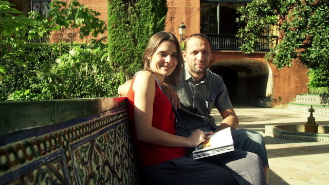 Portrait of happy couple sitting on bench in garden in Seville